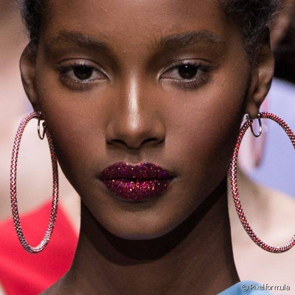 A grife Atelier Versace apresentou uma make com batom vermelho cheio de pigmentos coloridos e pele bem iluminada e real?ada na 'zona T'